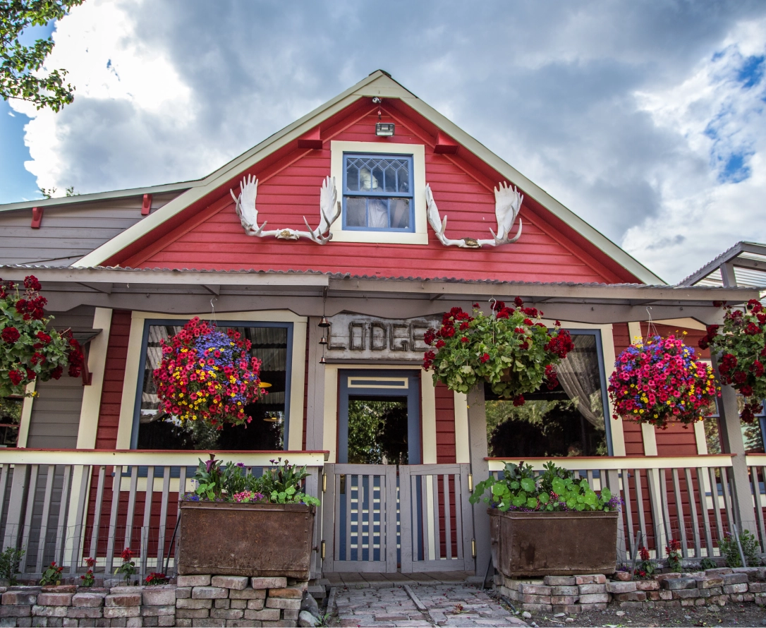 Quaint red lodge with antler decorations and flourishing flower baskets