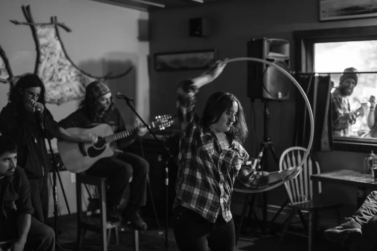 Live music performance in a rustic interior with musicians playing guitars.