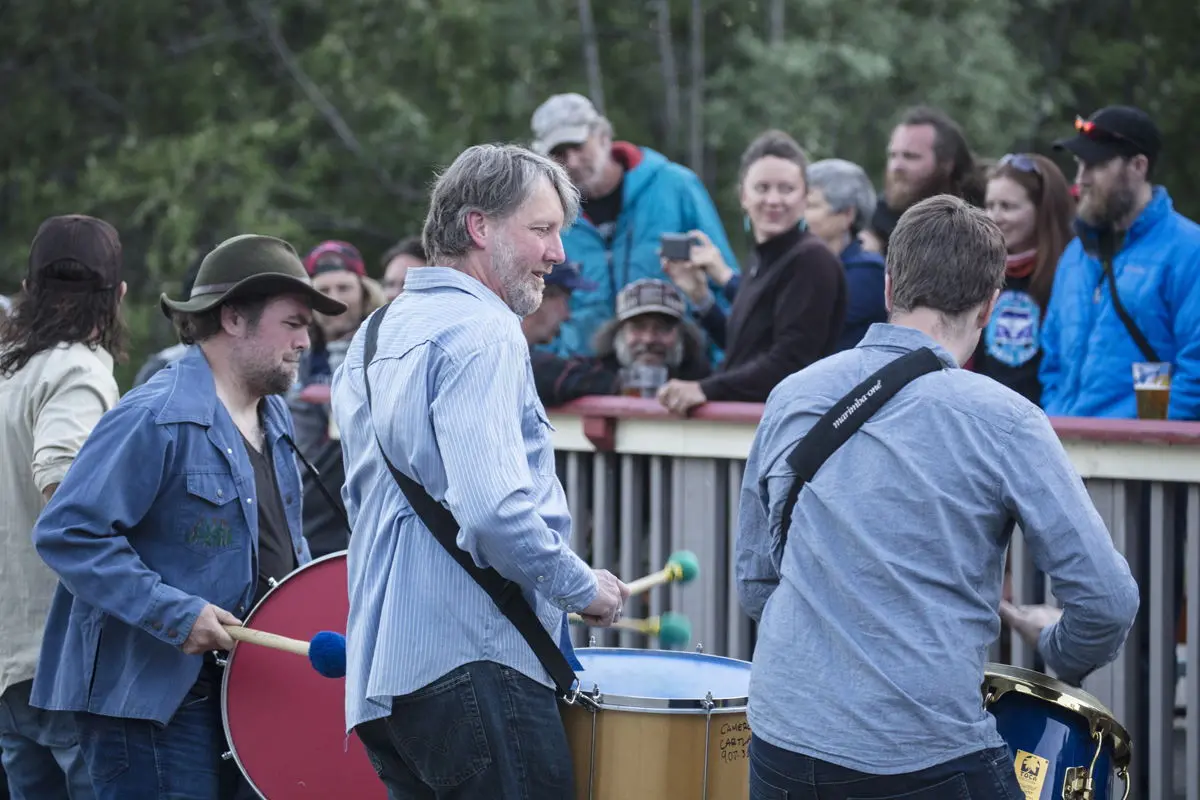 Group of people at an outdoor event with some playing musical instruments.