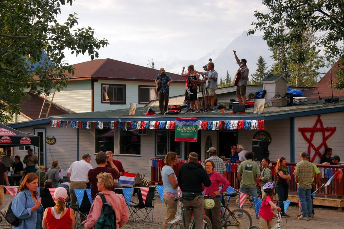 A band performs on a rooftop for an outdoor community event with mountain backdrop.