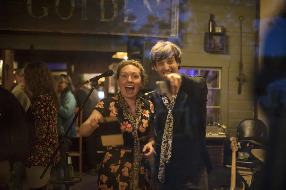 Two people at a music event with a microphone stand in the foreground.