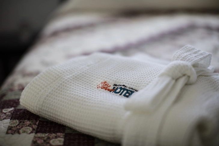 Folded white bathrobe on a patterned bedspread.