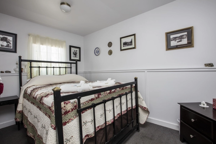 A cozy bedroom with a quilt-covered bed, wall decor, and a wooden nightstand.