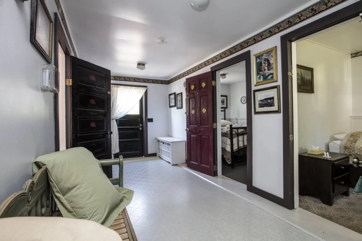 Interior of a home entryway with an open door, leading to a bedroom, decorated with photos and curtains.