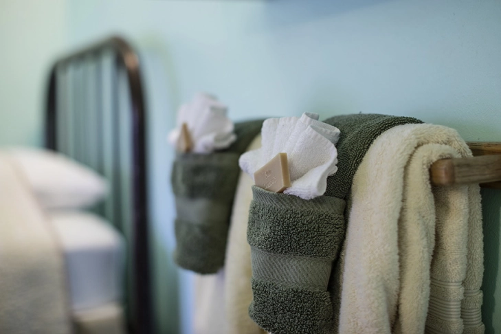 Towels and soaps on a wooden rack in a soft-lit bathroom setting.